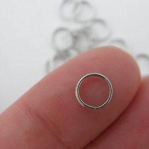 Könnte beinhalten: Nahaufnahme eines silbernen Sprungrings, eine Art Metallring, der in der Schmuckherstellung verwendet wird.