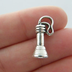 May include: Silver charm in the shape of a vintage rotary phone. The charm has a loop at the top for attaching to a necklace or bracelet.