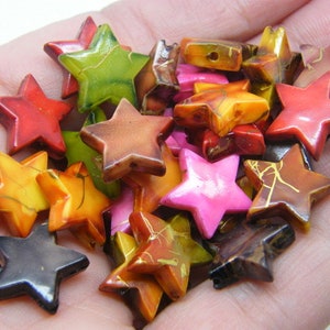 May include: A collection of colorful star-shaped beads made of wood with gold accents. The beads are in various shades of red, orange, yellow, green, brown, and pink.