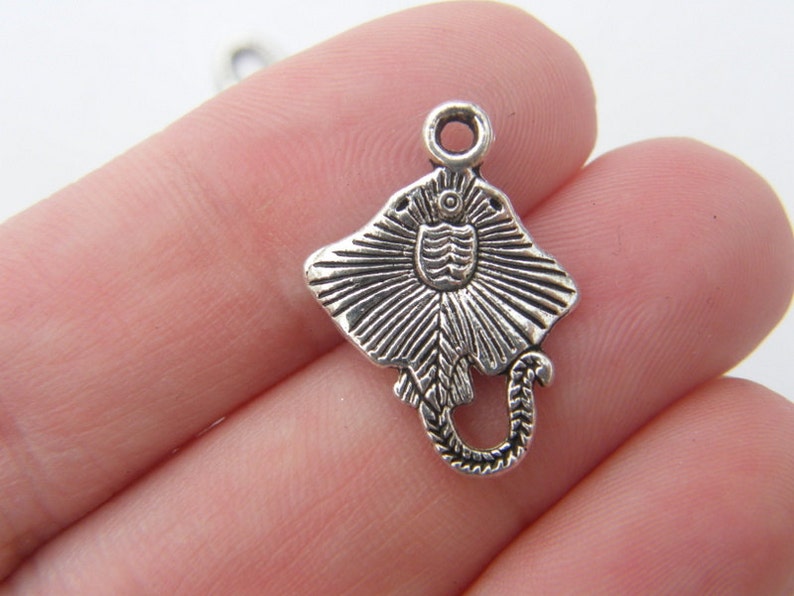 K&ouml;nnte beinhalten: Silberner Anh&auml;nger in Form eines Stachelrochens mit detailliertem Design. Der Anh&auml;nger hat oben eine &Ouml;se zum Anbringen an einer Halskette oder einem Armband.
