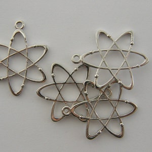 Op de afbeelding: Zilverkleurige atoombedelhangers. Elke bedel heeft een stervormig ontwerp met een centrale stervorm en draaiende lussen. De bedels hebben een kleine lus aan de bovenkant om aan sieraden te bevestigen.