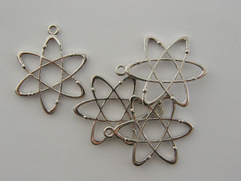Op de afbeelding: Zilverkleurige atoombedelhangers. Elke bedel heeft een stervormig ontwerp met een centrale stervorm en draaiende lussen. De bedels hebben een kleine lus aan de bovenkant om aan sieraden te bevestigen.