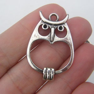 May include: Silver owl charm with an open center and a loop for attaching to a necklace or bracelet.