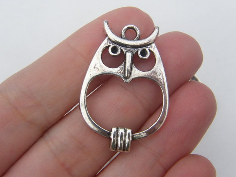 May include: Silver owl charm with an open center and a loop for attaching to a necklace or bracelet.