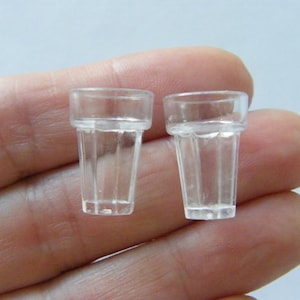 Op de afbeelding: Twee transparante miniatuur drinkglazen van plastic. De glazen zijn leeg en hebben een geribbeld ontwerp.