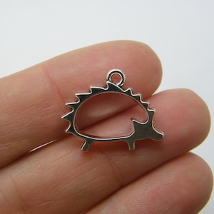 May include: Silver-toned metal charm shaped like a hedgehog. The charm has a loop at the top for attaching to a necklace or bracelet.