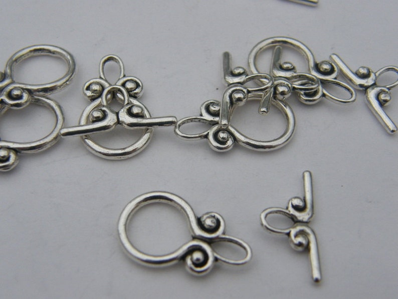 Pu&ograve; includere: Chiusure in metallo argentato con disegni decorativi, perfette per la creazione di gioielli o progetti di artigianato.