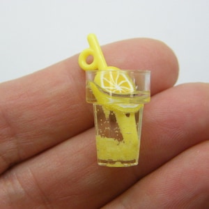 Könnte beinhalten: Ein gelbes Plastik-Miniatur-Glas Limonade mit einem gelben Plastikstrohhalm und einer Zitronenscheibe.