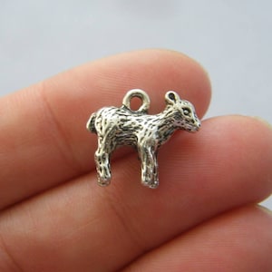 May include: Silver charm of a baby lamb, standing on all four legs. The charm has a textured surface to resemble fur.