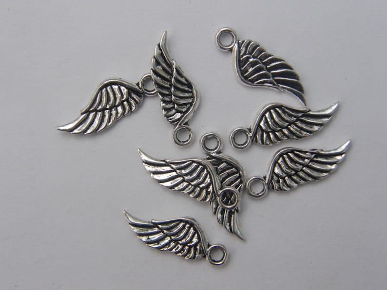 May include: A set of six silver-toned metal angel wing charms with a loop for attaching to jewellery or other crafts.