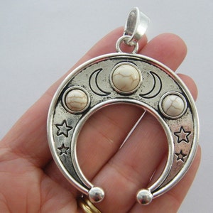 Op de afbeelding: Zilveren hanger met een halve maan ontwerp en witte stenen. De hanger heeft een lus aan de bovenkant om aan een ketting te bevestigen.