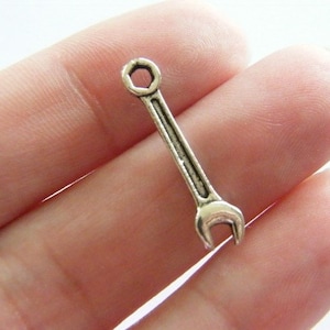 May include: Silver-toned wrench charm with a hexagonal head and a rounded handle. The charm is about 1.5 inches long.