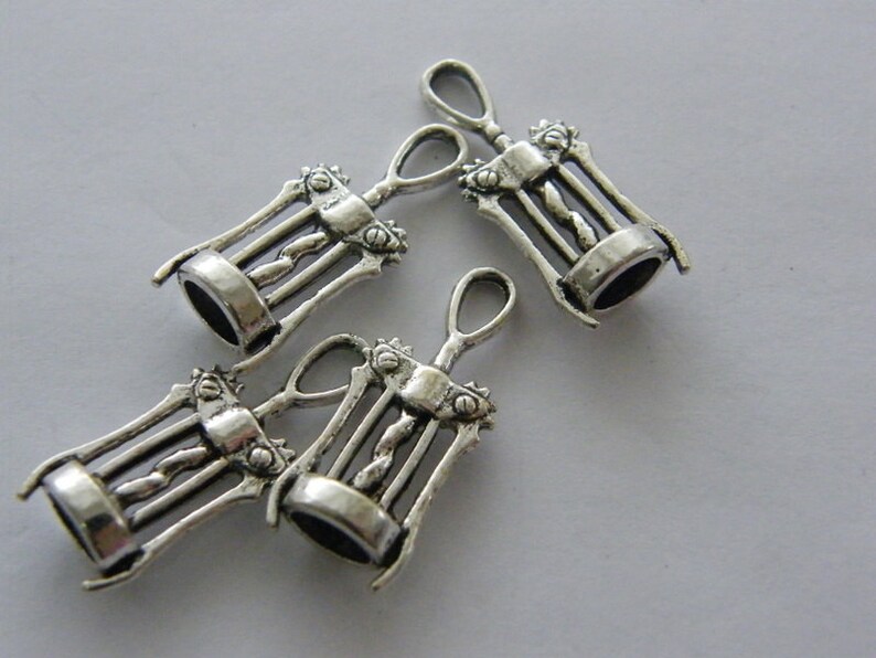 May include: Four silver-toned metal corkscrew charms. The charms are detailed with a corkscrew design and have a loop at the top for attaching to a necklace or bracelet.
