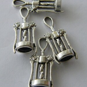 May include: Four silver-toned metal corkscrew charms. The charms are detailed with a corkscrew design and have a loop at the top for attaching to a necklace or bracelet.