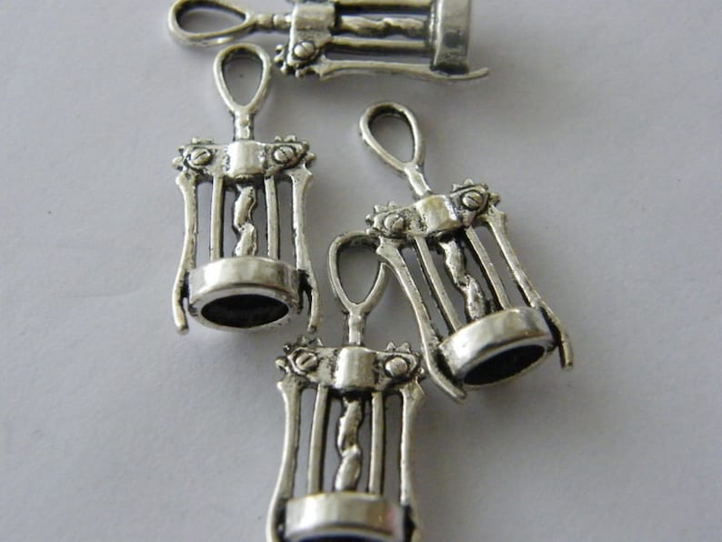 May include: Four silver-toned metal corkscrew charms. The charms are detailed with a corkscrew design and have a loop at the top for attaching to a necklace or bracelet.