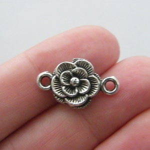 May include: Silver-toned metal flower charm with two loops for attaching to jewelry or other crafts.