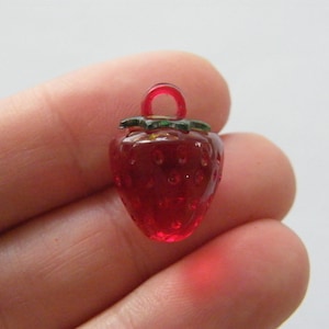 May include: A red glass strawberry charm with a green leaf and a gold loop for hanging.
