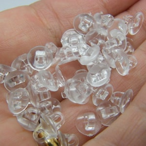 May include: A pile of clear plastic earring backs. The backs are designed to hold earrings in place.