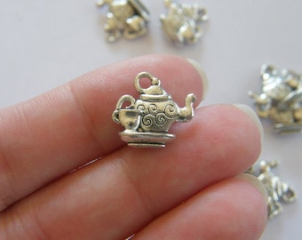 May include: Silver charm with a teapot and cup design. The teapot has a swirl pattern and a spout. The charm has a loop for attaching to a bracelet or necklace.