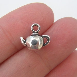 May include: Silver teapot charm with a loop for hanging. The charm is detailed with a spout, handle, and a textured surface.