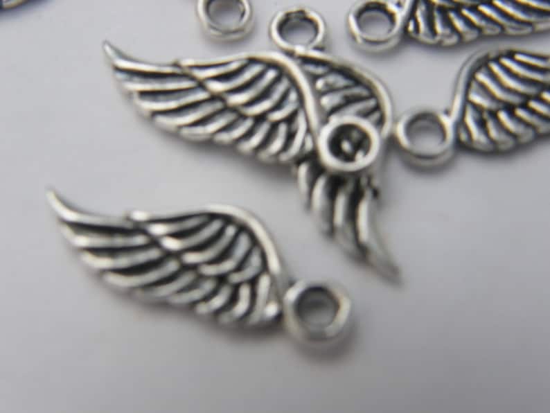 May include: Silver metal angel wing charms with a loop for attaching to jewellery or crafts.