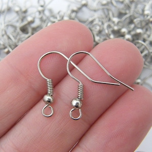 Puede incluir: Dos ganchos para pendientes de plata con un muelle en espiral y una pequeña bola en el extremo de cada gancho.