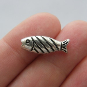 Può includere: Un ciondolo a forma di pesce argentato con strisce nere. Il ciondolo è lungo circa 2,5 cm e presenta un design dettagliato.