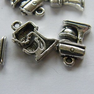 May include: Silver tone metal charms shaped like kitchen appliances, including a stand mixer, a blender, and a food processor. The charms have a detailed design and are perfect for adding a touch of whimsy to jewelry or crafts.
