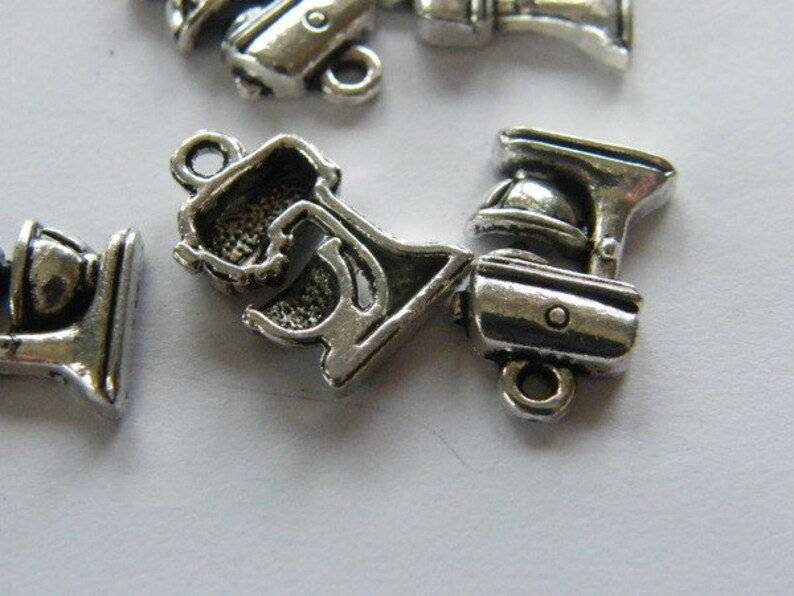 May include: Silver tone metal charms shaped like kitchen appliances, including a stand mixer, a blender, and a food processor. The charms have a detailed design and are perfect for adding a touch of whimsy to jewelry or crafts.