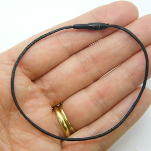 Pode incluir: Um cordão preto com um fecho de plástico. O cordão tem aproximadamente 45 cm de comprimento.