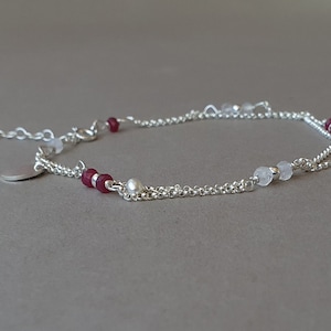 Puede incluir: Un delicado tobillo de cadena de plata con un pequeño dije de plata, con cuentas rojas y blancas.