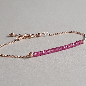 Op de afbeelding: Een delicate armband van roségoud met een enkele rij roze edelsteen kralen.