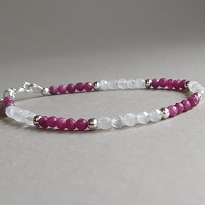 Könnte beinhalten: Ein zartes Armband mit abwechselnd weißen und rosafarbenen Perlen. Das Armband ist aus Silberperlen gefertigt und hat einen Verschluss.