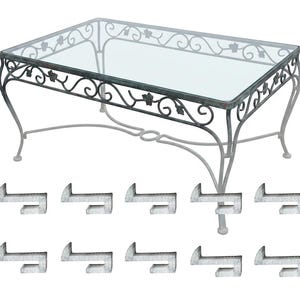 May include: A rectangular glass-top coffee table with a decorative wrought iron frame. The frame has a scrolling design with leaf accents and curved legs. Includes a set of ten metal clips.