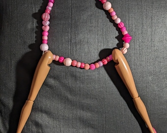 Pink beaded necklace with a pair of doll's legs