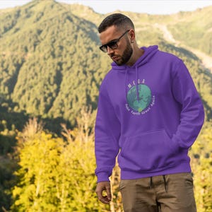 Peut inclure: Sweat-shirt &agrave; capuche violet avec un graphique d'une terre verte et bleue avec le texte "MEGA Make Earth Great Again" imprim&eacute; sur le devant.