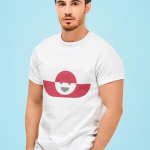 Peut inclure: T-shirt blanc avec un motif graphique ovale rouge et blanc avec un visage souriant. Le t-shirt est fait d'une mati&egrave;re douce et est port&eacute; par une personne aux cheveux fonc&eacute;s et &agrave; la barbe. Le fond est bleu clair.