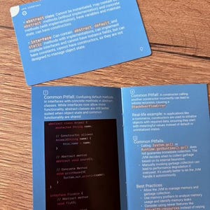 Puede incluir: Libro abierto y tarjeta con texto sobre conceptos de programaci&oacute;n Java. Las tarjetas azules y las p&aacute;ginas del libro muestran informaci&oacute;n sobre clases abstractas, interfaces y trampas comunes. El libro tambi&eacute;n muestra ejemplos de c&oacute;digo.