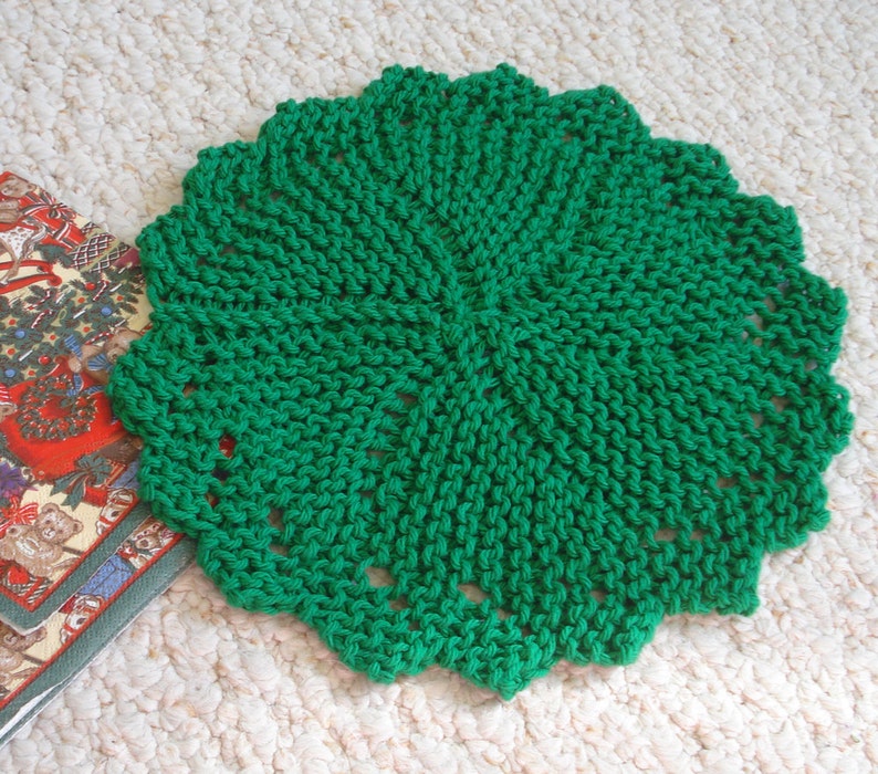 Op de afbeelding: Een groen gehaakt tafellaken met een rond ontwerp. Het tafellaken is gemaakt van fijn garen en heeft een delicate, kant-achtige uitstraling.