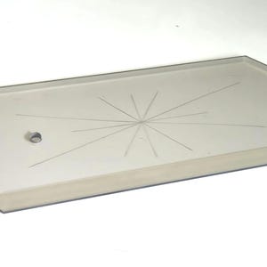 May include: A rectangular, light-colored glass tray with an octagonal shape and a starburst design etched into the surface. A small hole is visible near one end. The tray is likely used for serving or display.