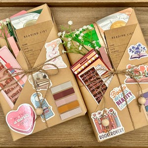 May include: Two brown paper parcels wrapped with twine and decorated with stickers. The parcels are labelled "Reading List" and include stickers with book-themed designs, such as a bookshelf, a heart with the text "My type is morally..." and a stack of books with the text "Books because reality is overrated".