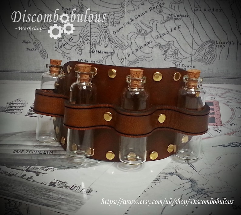 May include: A brown leather belt with six glass vials attached. The belt has gold metal rivets and is decorated with a wavy design. The vials are clear glass with cork stoppers.