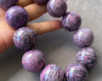 May include: A beaded bracelet featuring large, polished spherical beads in shades of purple, magenta, and black. Each bead displays a unique, swirling marbled pattern with glossy surfaces, arranged in a circular formation on a string.