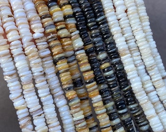 May include: Multiple strands of flat, circular shell beads arranged in a gradient of colors. The beads range from translucent white and cream to shades of golden yellow, brown, and deep black, each displaying a natural, iridescent luster.