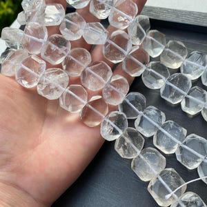 Pode incluir: Contas de pedras preciosas de quartzo transparente com um design geométrico facetado. As contas são enfiadas em um cordão branco. As contas têm uma aparência translúcida e são adequadas para fazer joias.