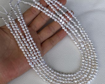 May include: Multiple strands of small, white, irregularly shaped freshwater pearls are strung together on thin, clear filament threads. Each strand features a series of lustrous, off-round pearls with a smooth, reflective surface texture.