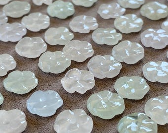 May include: A collection of small, translucent, flower-shaped beads carved from pale green and soft pink stone. Each bead features five rounded petals and a central hole, arranged in a grid pattern with a smooth, polished finish.