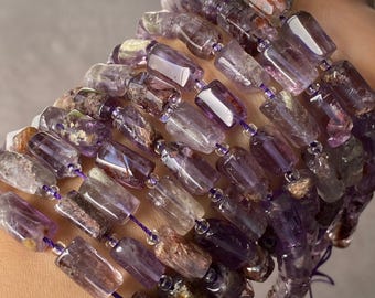 May include: A bracelet composed of multiple strands of rectangular, polished amethyst beads. The beads feature translucent purple hues mixed with opaque, earthy brown and dark inclusions, strung together on thin, vibrant purple thread.