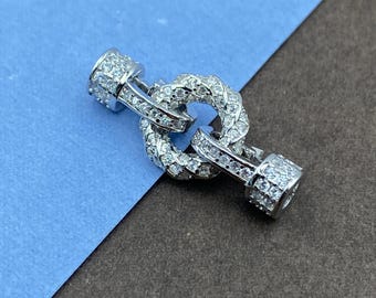 May include: A silver-toned toggle clasp for jewelry featuring a circular ring and a bar component, both encrusted with numerous small, clear, sparkling stones. The metal surfaces are fully paved with these stones, creating a bright, reflective appearance for this functional jewelry connector piece.