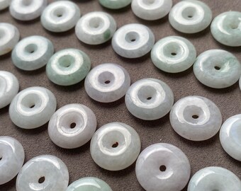 May include: A collection of circular jade beads arranged in rows. Each bead features a smooth, polished surface with a central hole, displaying variations of pale green, white, and translucent tones throughout the set of jewelry components.